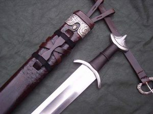 Sword with ornate sheath on fabric background.