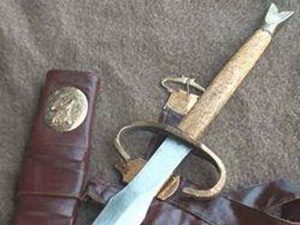 Antique dagger with sheath on fabric background.