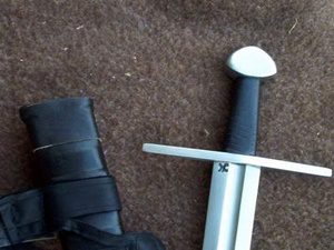Sword and black glove on brown fabric.
