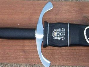 Sword with ornate hilt on wooden surface.