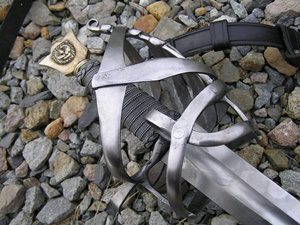 Sword with intricate hilt on rocky ground.