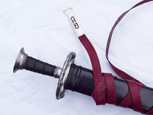 Sword with maroon strap on white background.