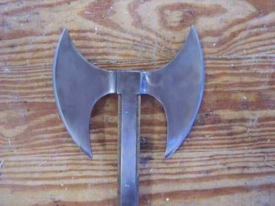 Double-headed battle axe with a wooden handle on a wooden surface.