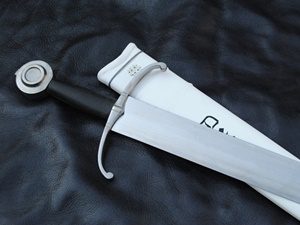 Sword with sheath on dark leather background.