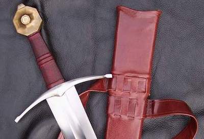 A close-up of a sword next to a brown leather sheath.