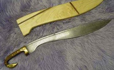 Two traditional curved blades with sheaths resting on a soft surface.