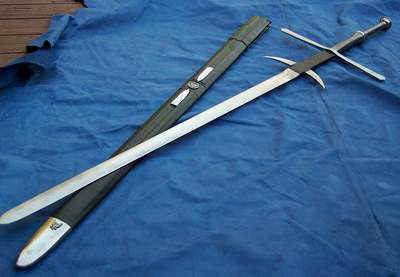 A medieval longsword with a black sheath on a blue cloth.