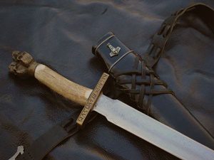 Sword with ornate scabbard on leather background.