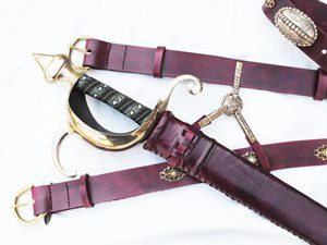Sword with ornate hilt and leather scabbard.