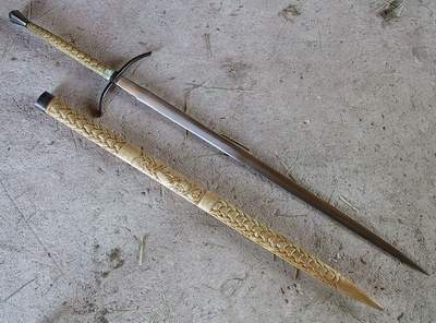 A rusty old sword with a wooden handle lying on a concrete surface.