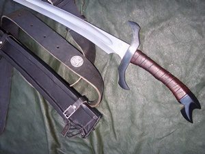 Sword and leather belt on green fabric.