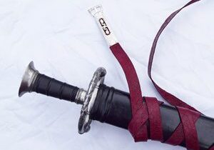 Sword with maroon strap on white background.