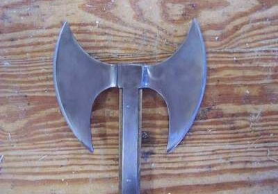 Double-headed battle axe with a wooden handle on a wooden surface.